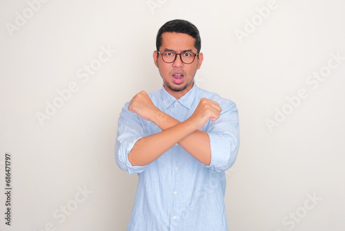 Adult Asian man making cross sign with his hand with serious expression photo