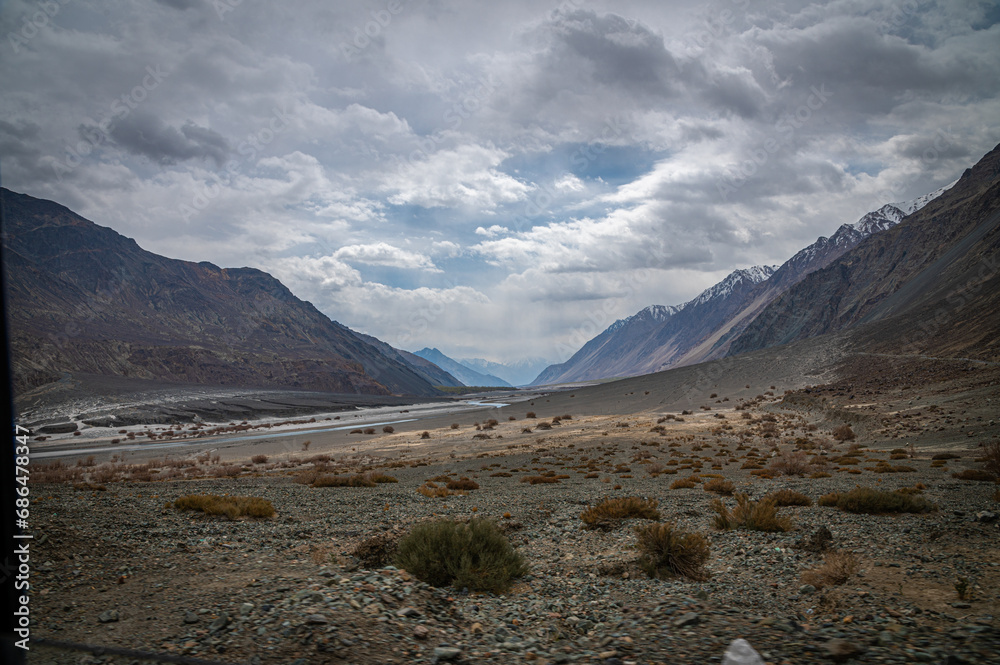 Scenic view of Himalayas and Ladakh ranges. Beautiful barren hills in Ladakh with dramatic clouds in the background.  View from the road from Nubra Valley to Turuk. Siachen area in Leh Ladakh.