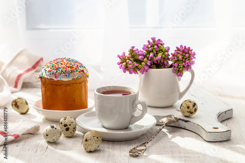 Easter still life with painted eggs  Easter cake and tea in a cup on the windowsill on a sunny day