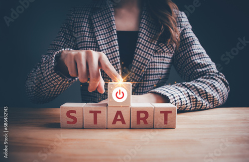 Businesswoman hand pressing start button and wooden blocks with START text. Start up business, make a new start, restart in life, Investor accelerate start-up project, education or career concept.