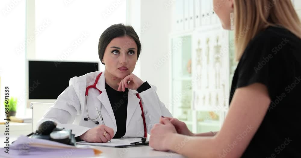 Female doctor in office takes notes during meeting with patient Female doctor in office takes notes during meeting with patient