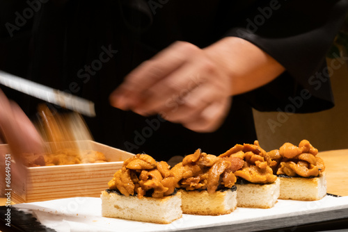 Omakase fresh uni sushi menu with professional chef hand cooking Asian traditional food for dinner meal in kitchen counter at Japanese restaurant