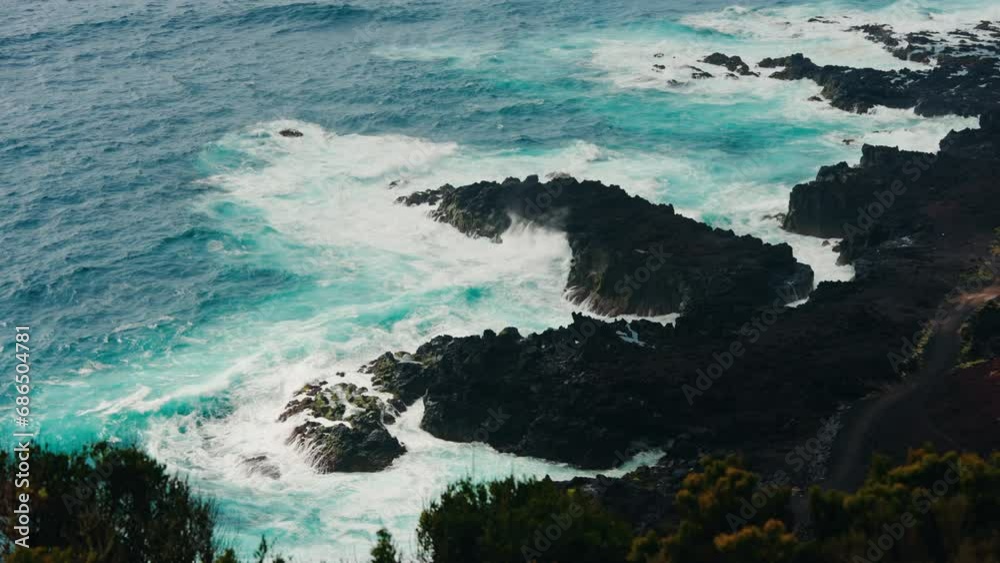 Slow motion wide shot of rocky coastline. Colorful turquoise ocean waves crushing on the rocks. Slow motion wide shot of rocky coastline. Colorful turquoise ocean waves crushing on the rocks.