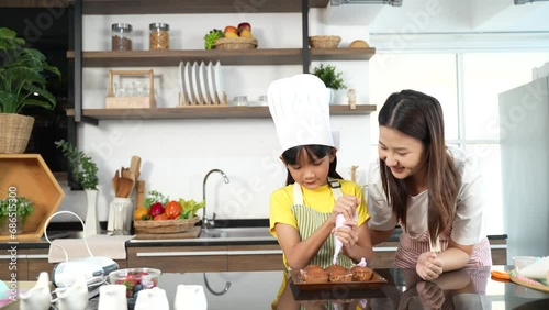 Small girl enjoying making cake with her mother in kitchen at home