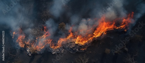 A fire in the forest and field. Burned dry grass, a natural disaster. Seen from above. Ground covered in black burning ash. Vertical view from low height.