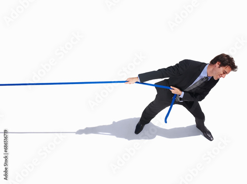 Businessman, frustrated and tug of war by white background, career challenge and industry competition. Young person, mental health and professional worker with rope, top view and job battle in studio