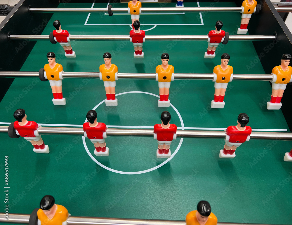 Football - board game with players, soccer ball and green field. Foosball table, close-up. Football - board game with players, soccer ball and green field. Foosball table, close-up.