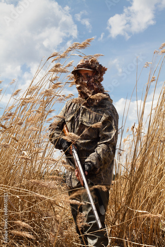 A camouflaged duck hunter stands in the reeds photo