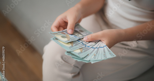 Portrait close up of young asian woman counts cash dollar bills while sitting in living room at home,counting stack cash money dollar, Financial planning.