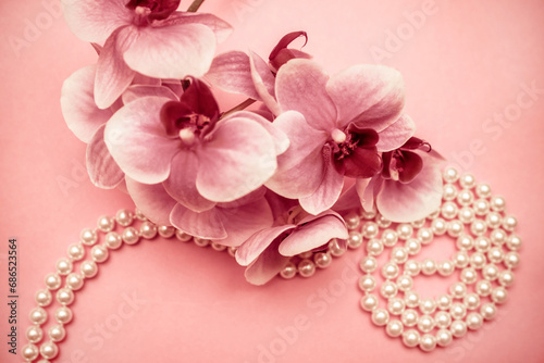 Pearl necklace and purple orchid on pink background 