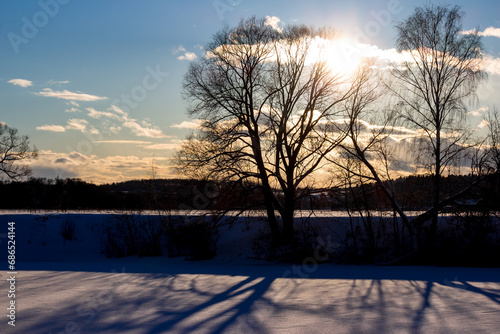 The sun in the sky leaning toward sunset against the backdrop of winter nature