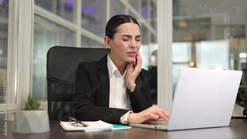 Unhappy female manager working on digital laptop and raising hand to cheek while feeling severe toothache. Caucasian lady dressed in classic style sitting in office and feeling bad because of pain. Unhappy female manager working on digital laptop and raising hand to cheek while feeling severe toothache. Caucasian lady dressed in classic style sitting in office and feeling bad because of pain.