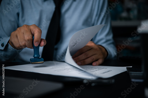 Hand man stamping documents notary public in office . Businessperson stamping approval of work finance banking or investment marketing documents on desk.. photo