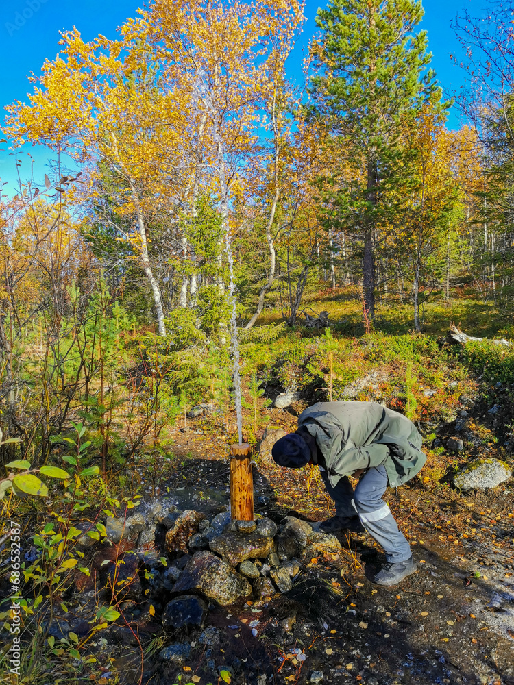 A man on the background of the autumn Arctic landscape in the Khibiny mountains. Kirovsk, Kola Peninsula, Polar Russia. Autumn colorful forest in the Arctic, mountain hikes and adventures.