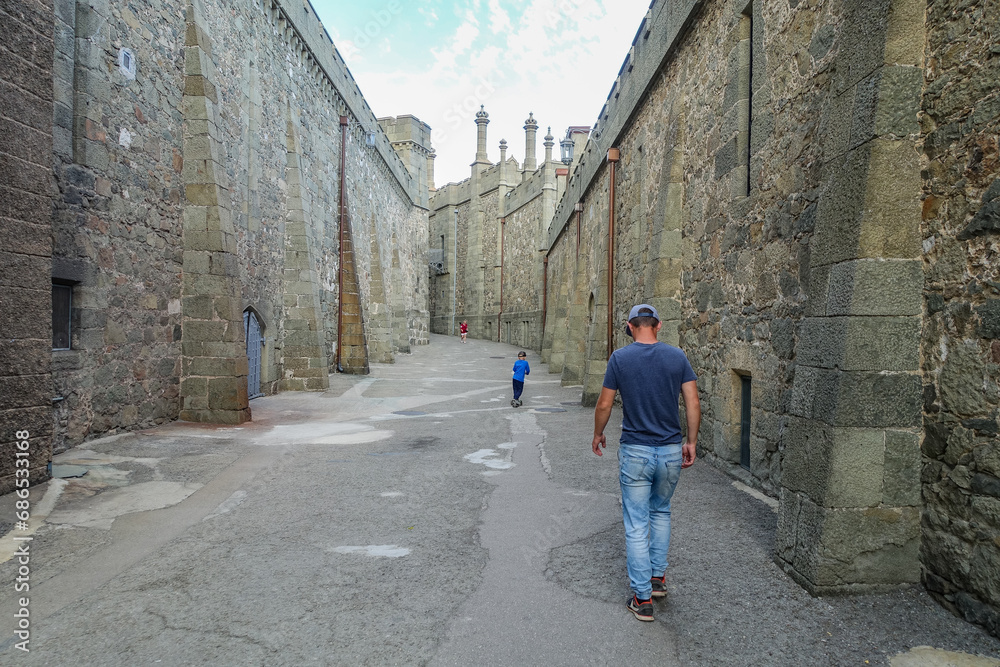 A man with a child on the background of the Vorontsov Palace in the Crimea in summer. Ancient walls with many columns, turrets and domes. An architectural masterpiece. A man with a child on the background of the Vorontsov Palace in the Crimea in summer. Ancient walls with many columns, turrets and domes. An architectural masterpiece.