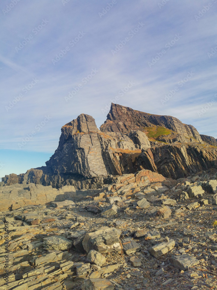 The rocky coast of the Barents Sea. Beautiful view of the rocks and the coast of the Rybachy and Sredny peninsulas, Murmansk region, Russia. The landscape is the harsh beauty of the north. The rocky coast of the Barents Sea. Beautiful view of the rocks and the coast of the Rybachy and Sredny peninsulas, Murmansk region, Russia. The landscape is the harsh beauty of the north.