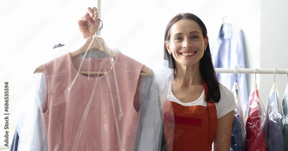 Woman giving out clean clothes in plastic bags to client in laundry 4k movie slow motion. Dry cleaning service concept