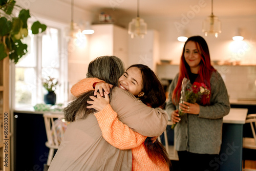 Happy girl embracing grandmother and greeting at home photo