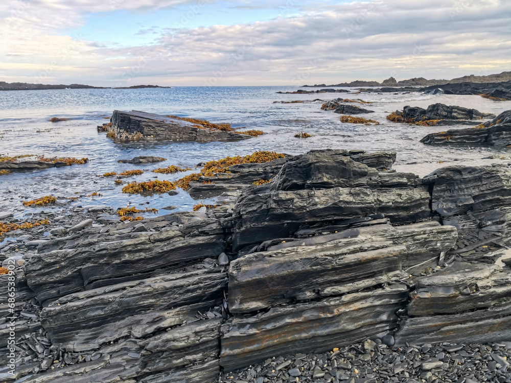 The rocky coast of the Barents Sea. Beautiful view of the rocks and the coast of the Rybachy and Sredny peninsulas, Murmansk region, Russia. The landscape is the harsh beauty of the north. The rocky coast of the Barents Sea. Beautiful view of the rocks and the coast of the Rybachy and Sredny peninsulas, Murmansk region, Russia. The landscape is the harsh beauty of the north.