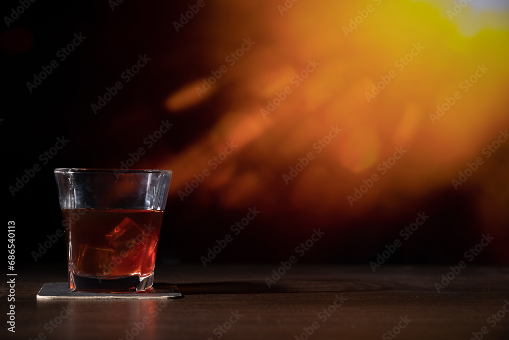 Glass of whiskey on the bar in front of the blur image Abstract Natural Sun flare on the black Glass of whiskey on the bar in front of the blur image Abstract Natural Sun flare on the black