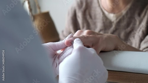 A manicurist wearing white gloves does his job. Manicure process in a beauty salon close-up. Cuticle removal. Self care concept. photo