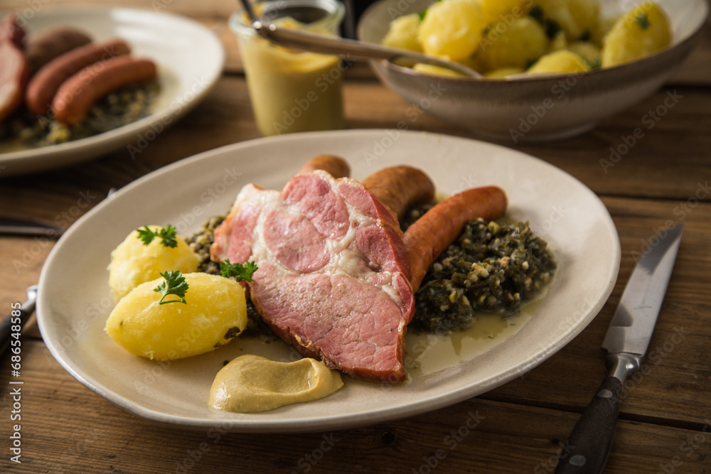 2 Portionen Oldenburger Grünkohl mit geräucherter Kohlwurst, Pinkel, Kassler Nacken, Kartoffeln, Senf, Petersilie auf Teller und Holz Hintergrund 2 Portionen Oldenburger Grünkohl mit geräucherter Kohlwurst, Pinkel, Kassler Nacken, Kartoffeln, Senf, Petersilie auf Teller und Holz Hintergrund
