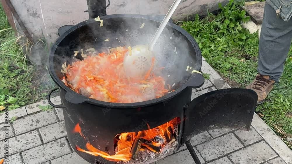 Frying meat with carrots in a cauldron over a fire Frying meat with carrots in a cauldron over a fire