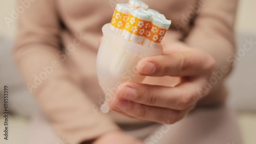 Reusable and eco-friendly option. Recyclable and reusable feminine care. Feminine hygiene for everyday life. Closeup of woman hands showing collector menstrual cup and tampon photo