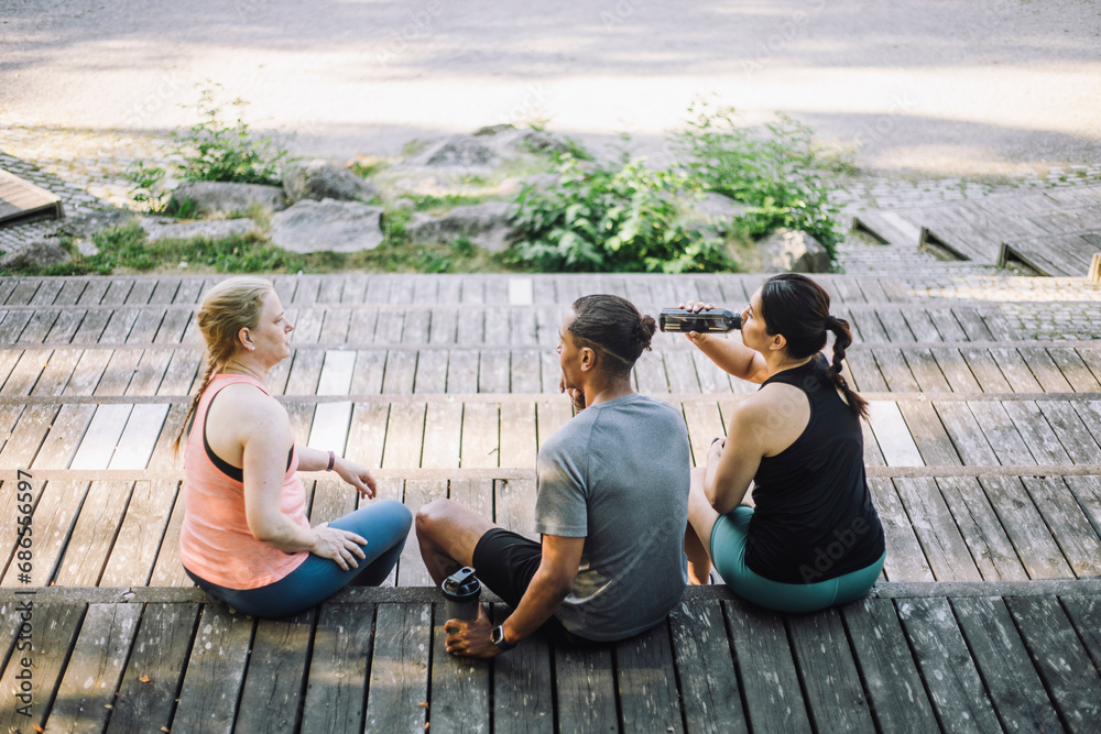 High angle view of male and female friends sitting on steps during break after work out High angle view of male and female friends sitting on steps during break after work out