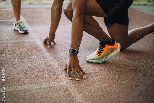 Low section of man kneeling at starting line on running track photo