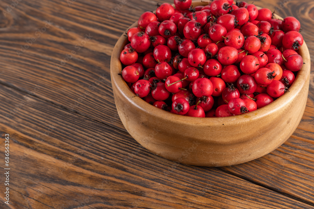 red hawthorn berries in wooden bowl on flat wooden surface. red hawthorn berries in wooden bowl on flat wooden surface.