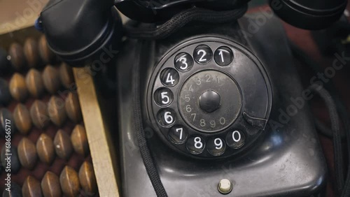 An antique black dial phone is on the table. Shooting from above photo