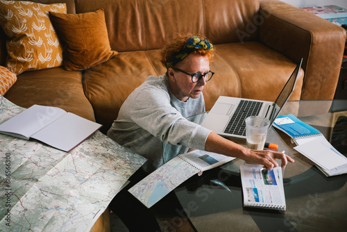 Elderly woman with map and documents planning trip at home photo