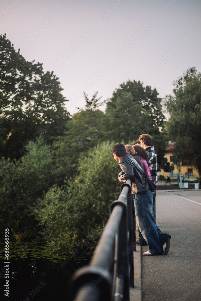Male and female teenage friends leaning on bridge railing Male and female teenage friends leaning on bridge railing
