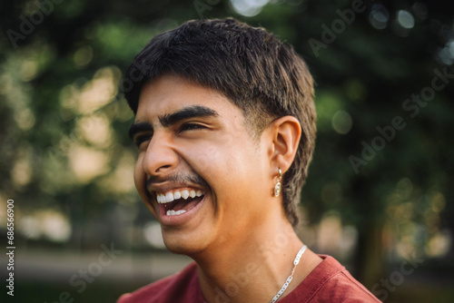 Happy teenage boy laughing at park photo