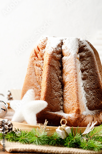 Traditional Italian Christmas sweet bread Pandoro with vanilla-scented icing sugar and Christmas decorations on light background. Close up.