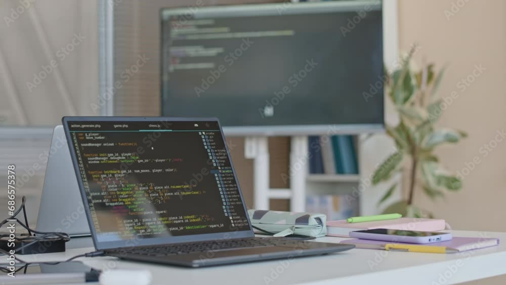 Selective focus shot of laptop with programming code on screen in empty school classroom during daytime