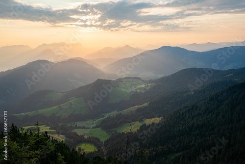 Idyllic landscape of a mountainous backdrop draped in vibrant green foliage with a brilliant sunset