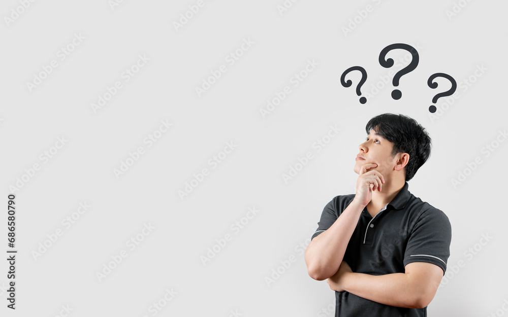 Asian man looks up with a curious expression and a question mark. with copy space and business design research studies Asian man looks up with a curious expression and a question mark. with copy space and business design research studies