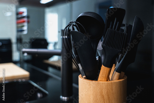 utensilios de cocina negros en un recipiente de madera moderno photo