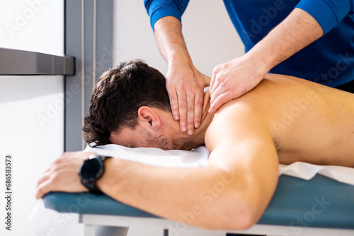 An unrecognizable physiotherapist massages a man's neck inside a clinic. Decontracting massage. Stress release. Nerve lash in men. photo