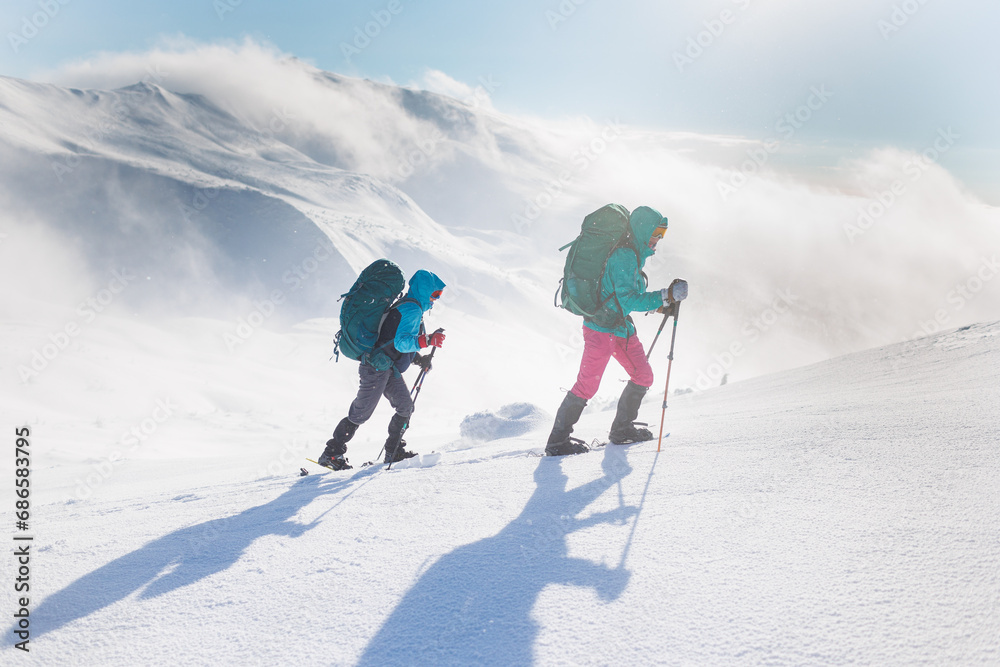 climbers climb the mountain in the snow. Winter mountaineering. two girls in snowshoes walk through the snow. mountaineering equipment. hiking in the mountains in winter.