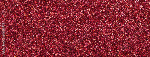 Dark red sparkling background from small sequins, macro. Wine shiny backdrop with glitter pattern
