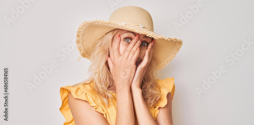 Fotografie Portrait of woman covering eyes with hand, peeking through fingers isolated on w