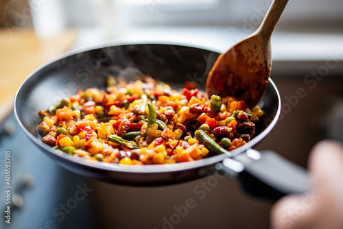 cooking tasty vegetable mix with corn, pea, beans in pan on kitchen photo
