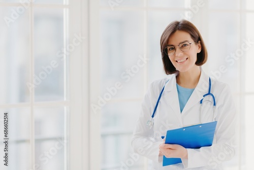 Happy female doctor with clipboard in a bright office, healthcare professional.