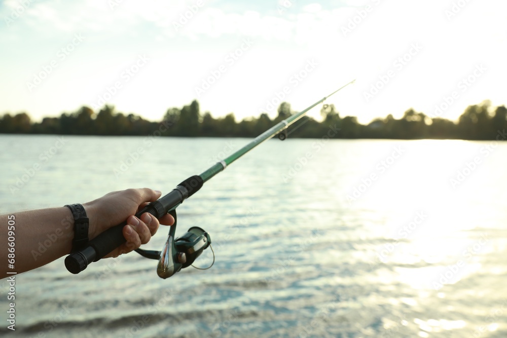 Fisherman with rod fishing at riverside, closeup. Space for text Fisherman with rod fishing at riverside, closeup. Space for text
