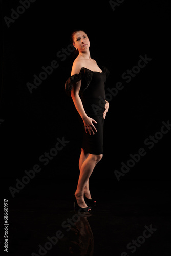 brunette woman posing in black studio