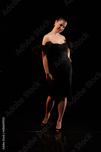 brunette woman posing in black studio