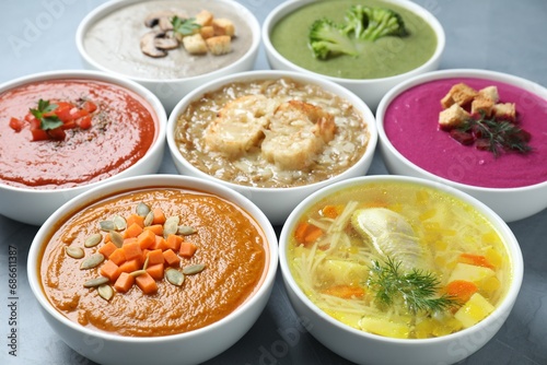 Tasty broth and different cream soups in bowls on gray table, closeup